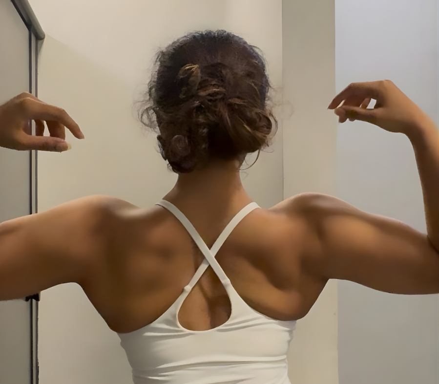 A woman at the gym showing her back and arm muscles, representing strength and a weightlifting lifestyle.